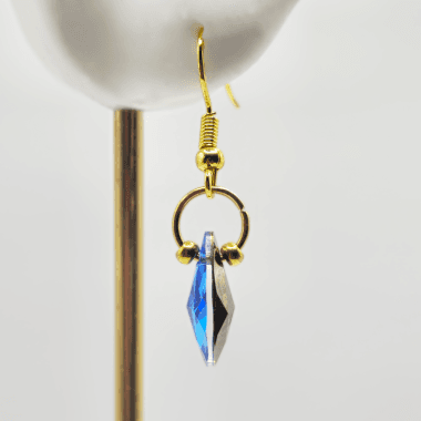 Goudkleurige oorhangers met blauwe druppel in oor