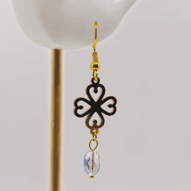 Goudkleurige oorhangers met klavertje vier en steen in oor